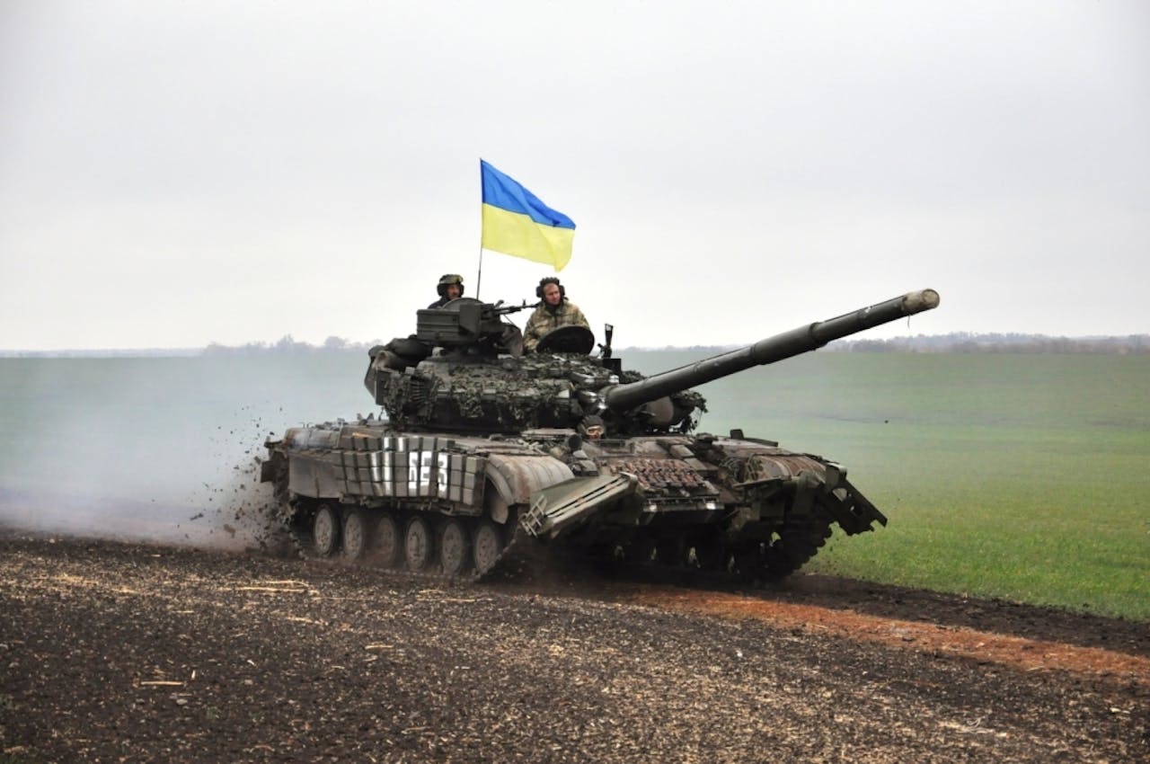 Russische tanks op een weg met bergen op de achtergrond.