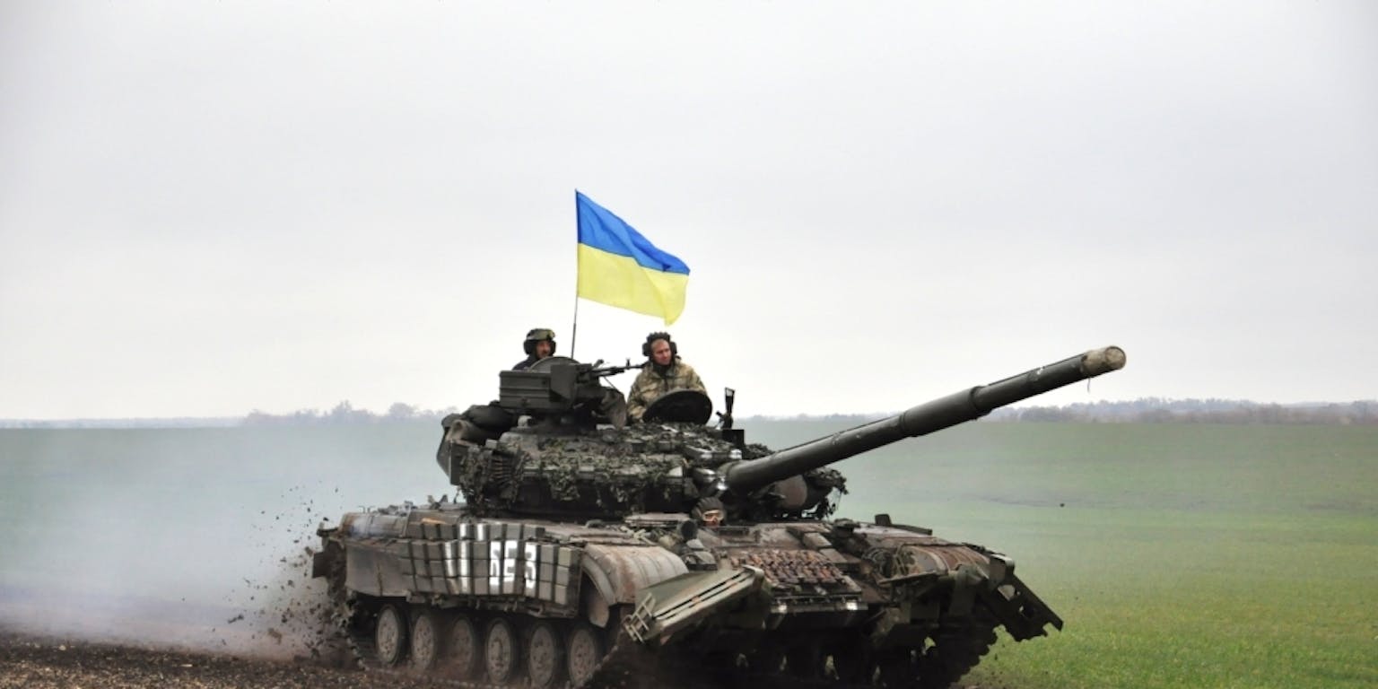 Russische tanks op een weg met bergen op de achtergrond.