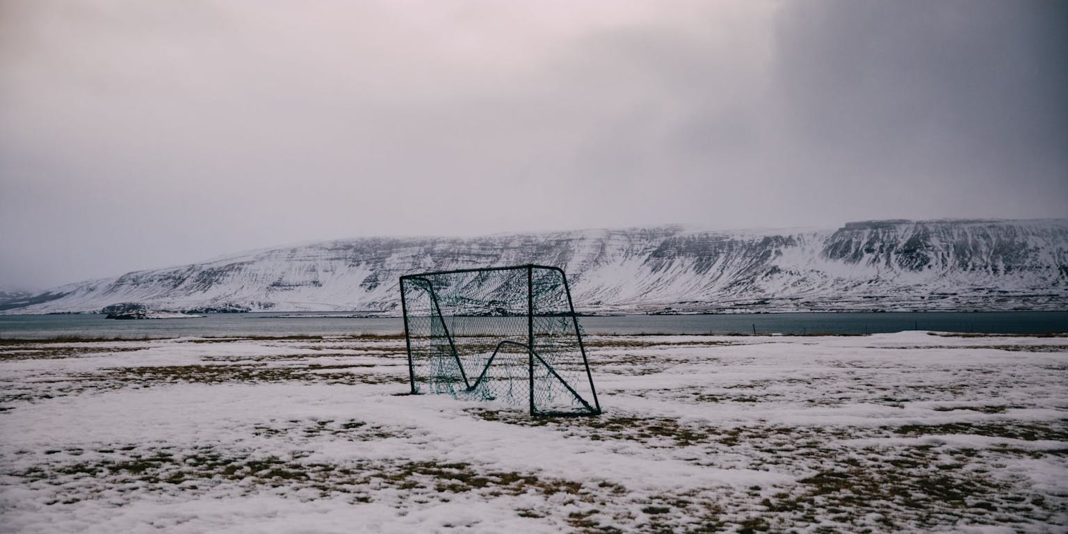 Een besneeuwd veld met een blauw hek op de achtergrond.