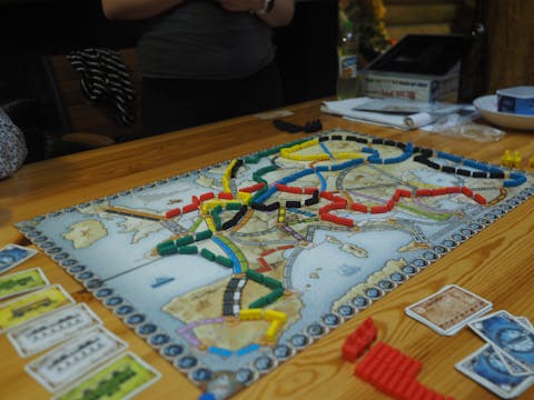 Ticket to Ride is een ‘perfect bedacht spel’, aldus Marcus du Sautoy. Een kaart van Europa vormt het bord van een spel. Daarop lopen slingers van rode, gele, groen en blauwe pionnen. Naast het bordspel liggen speelgoedgeld en kaarten op tafel.