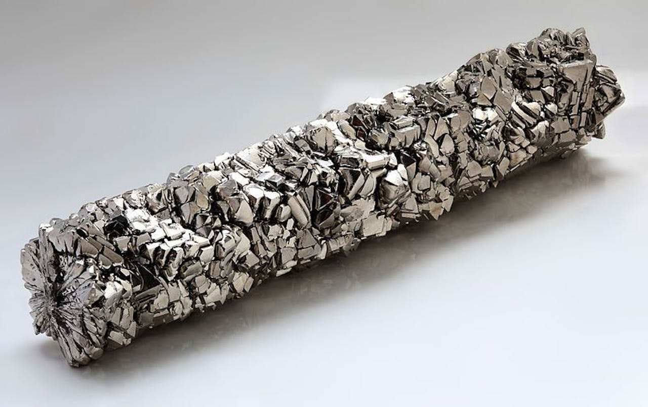 Een staaf van titanium kristallen op een lichte achtergrond.