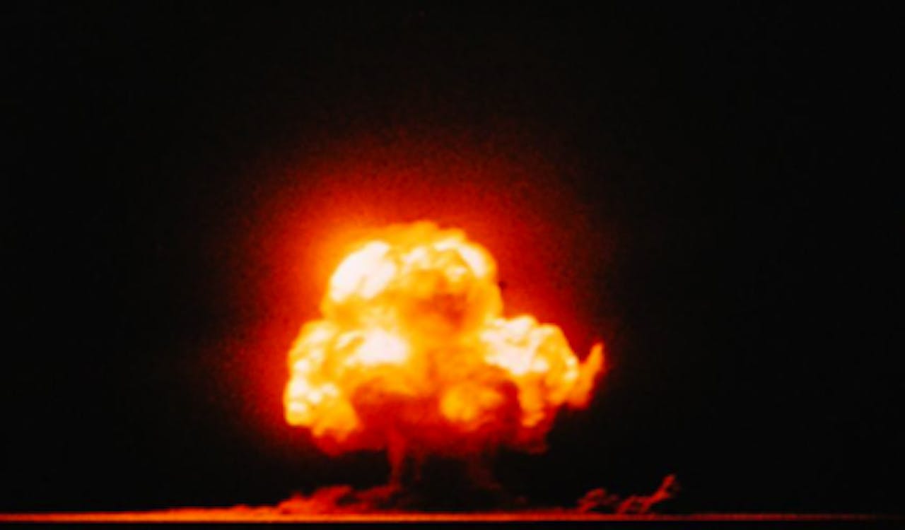 Een oranje-rood gloeiende ontploffingswolk van een atoomboom.