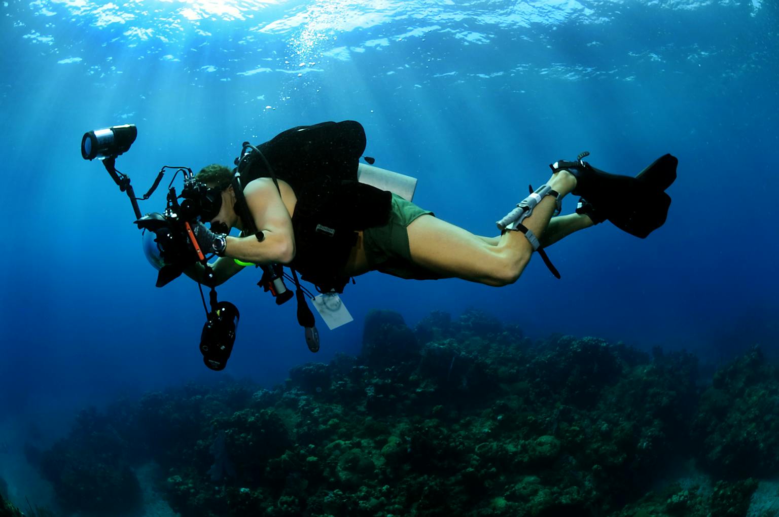 Een duiker met een camera onder water.