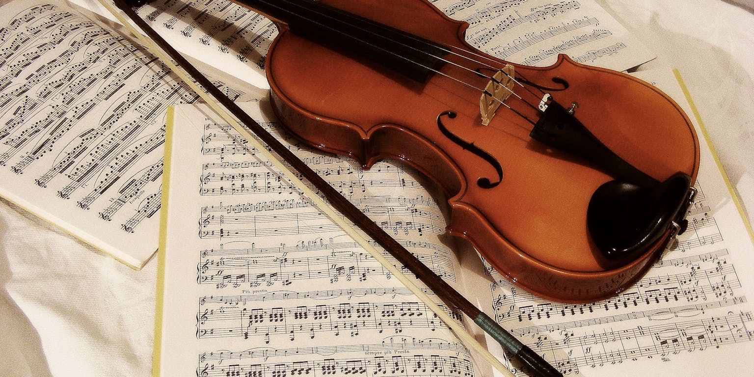 Een viool staat bovenop een muziekblad.