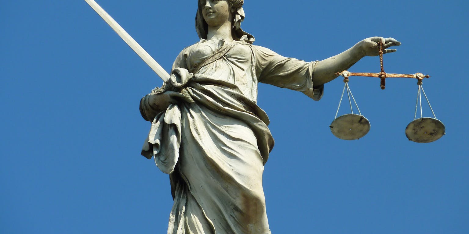 Een beeld van Vrouwe Justitia met een zwaard en een weegschaal.