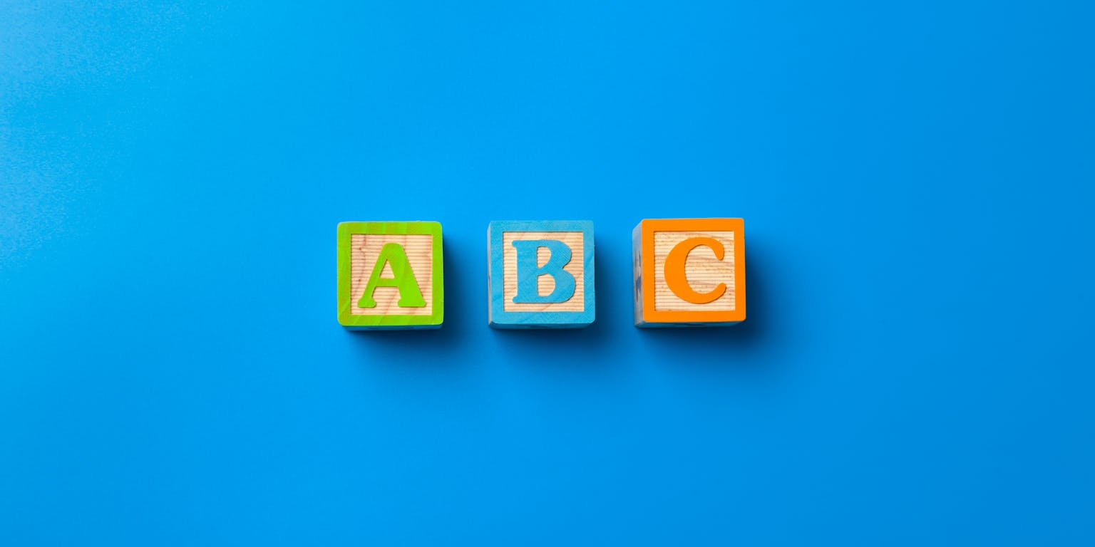 houten blokjes met a b en c op een blauwe achtergrond