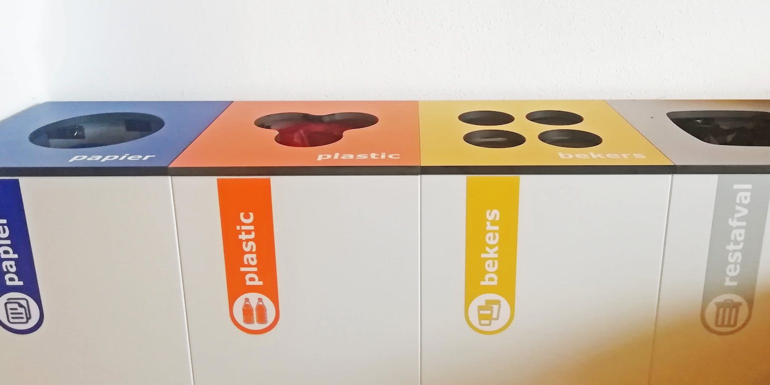 Een groep verschillend gekleurde recyclingbakken die naast elkaar zitten.
