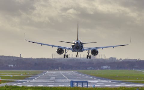 Een vliegtuig landt op een luchthaven. Een vliegtuig gezien vanaf de achterkant hangt boven de landingsbaan.
