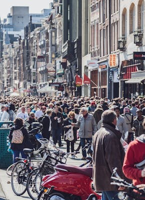 Een menigte mensen die door een straat in Amsterdam loopt.