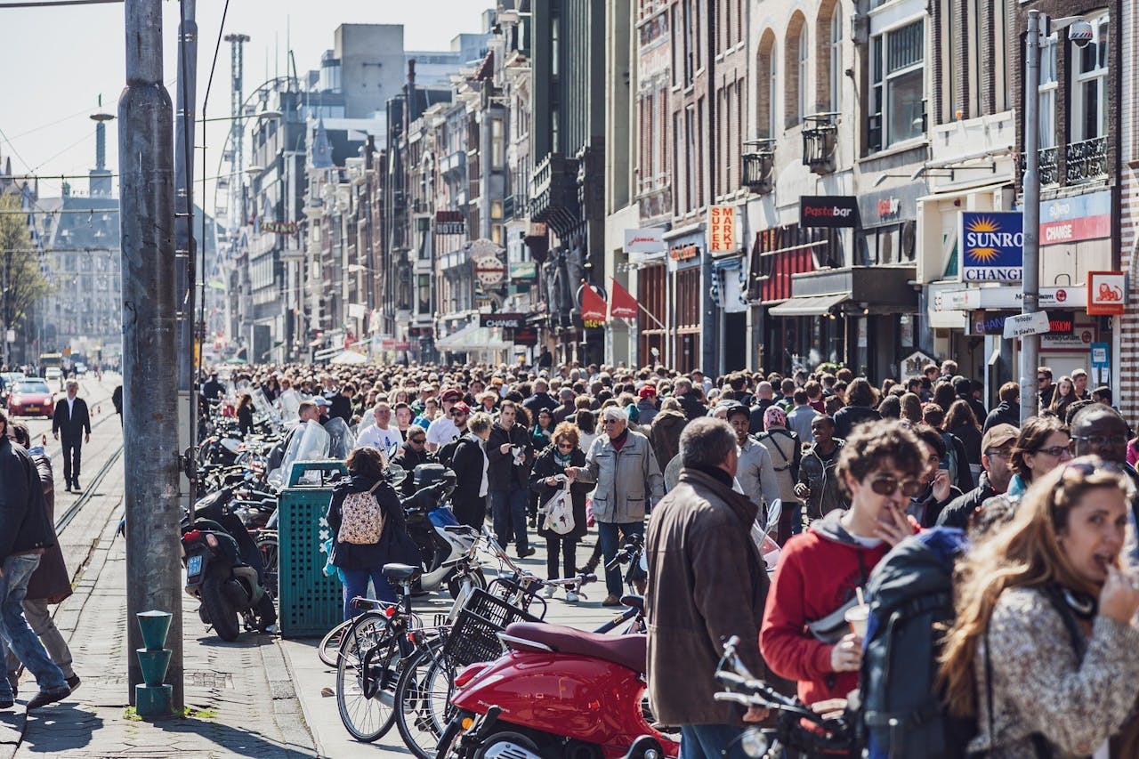 Een menigte mensen die door een straat in Amsterdam loopt.