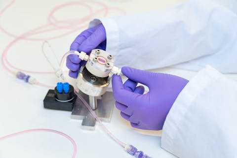 Een organ-on-a-chip met een leverorganoïde. Close-up op de gehandschoende handen van een onderzoeker die aan het werk is met een organ-on-a-chip.