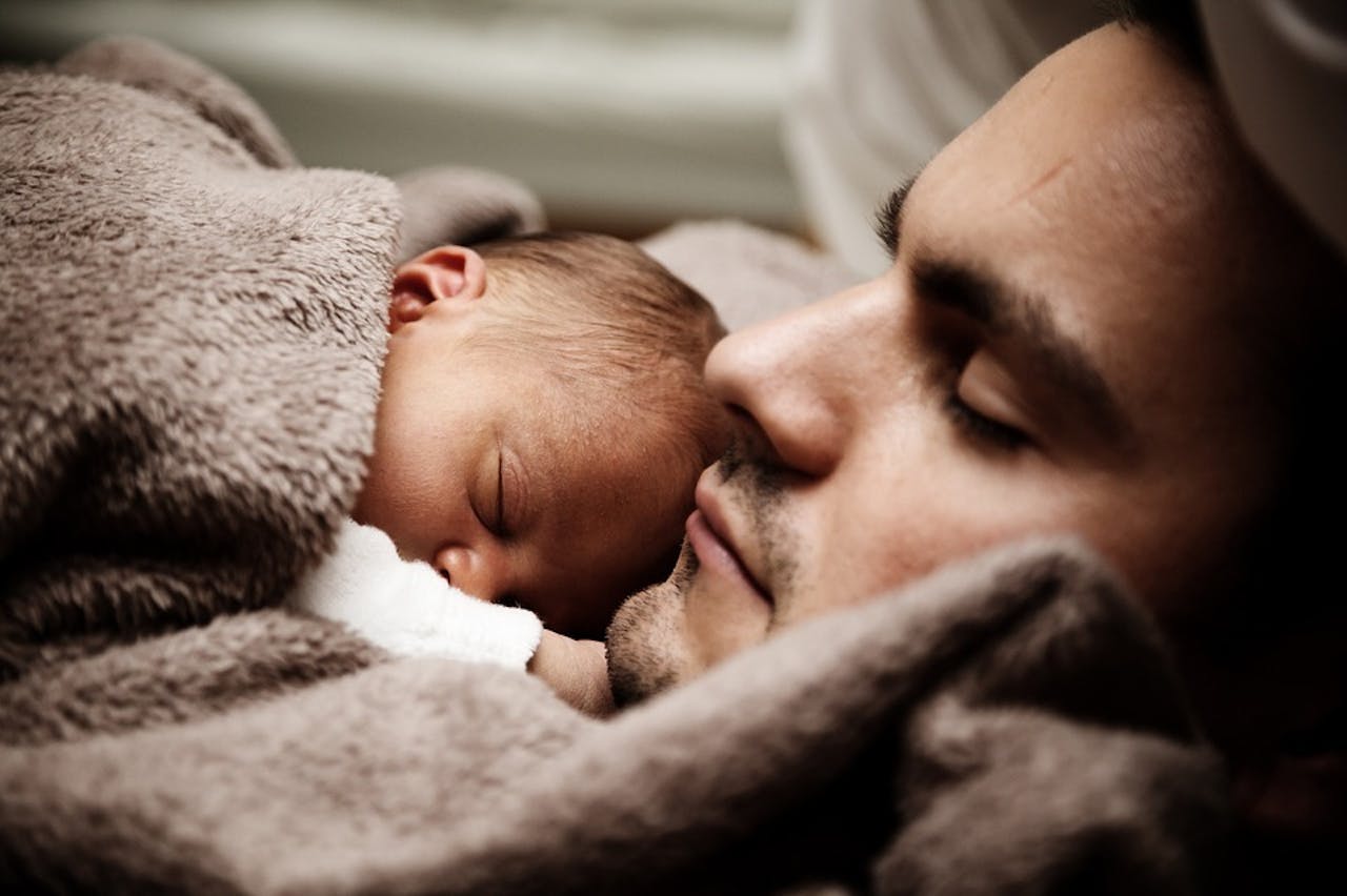 Een persoon houdt een baby vast, gewikkeld in een deken.