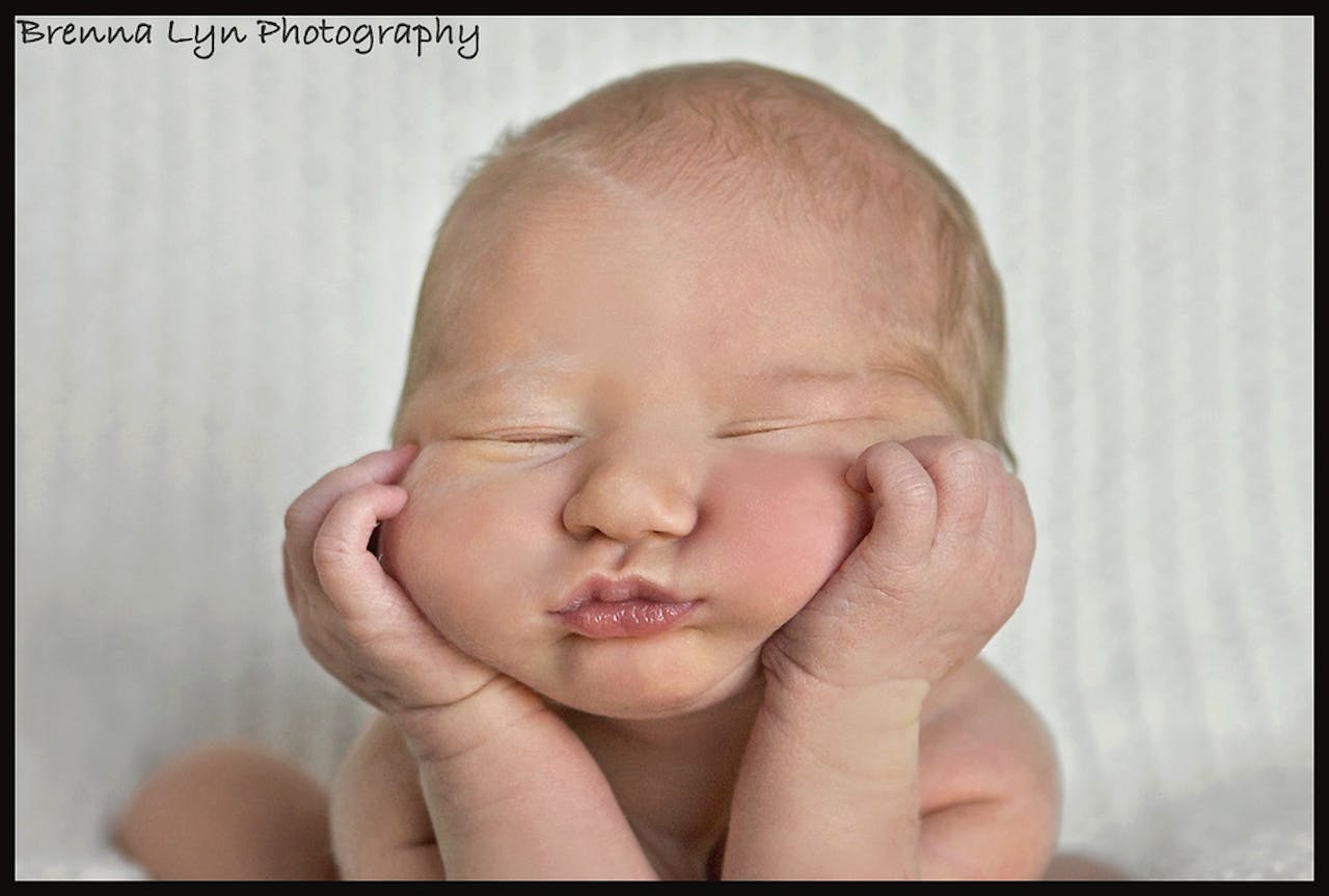 Een baby ligt op een vloer vol roze bloemblaadjes.