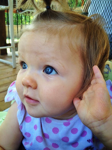 Een close up van een babygezicht met fel blauwe ogen.