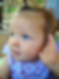 Een close up van een babygezicht met fel blauwe ogen.