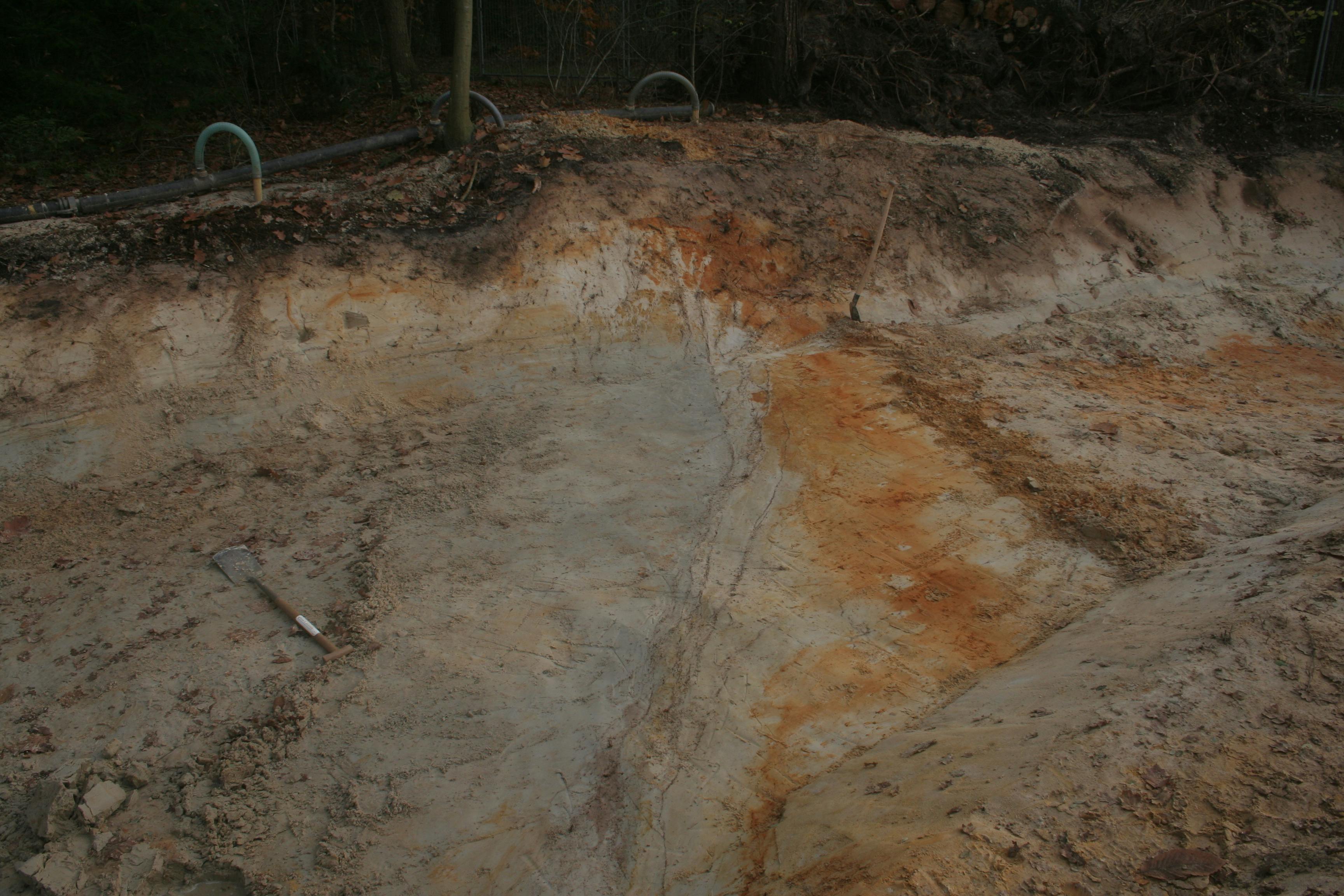 Een gegraven zandkleurige sleuf met schop in Bakel