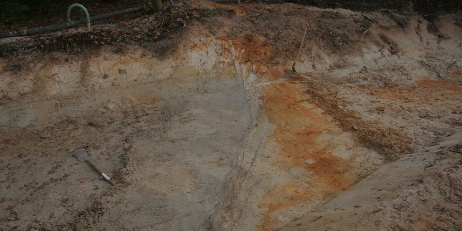Een gegraven zandkleurige sleuf met schop in Bakel