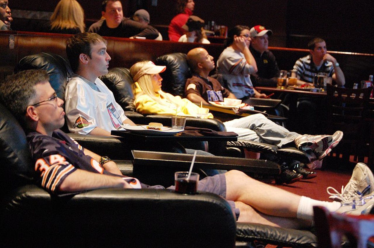Een groep mensen die een film kijken in luxe ligstoelen.