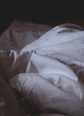 Een afbeelding van een bed met een deken erop.