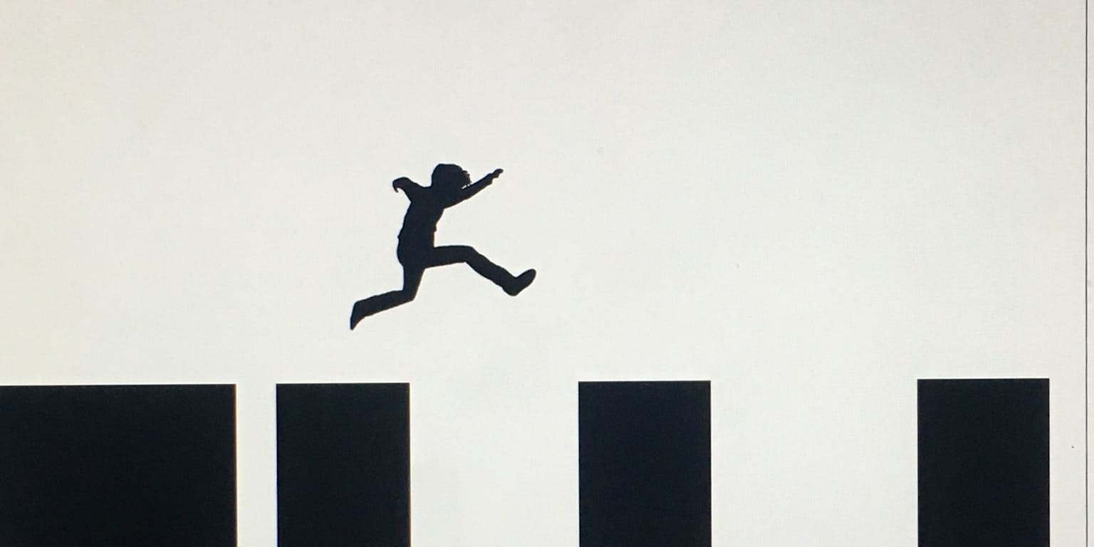 Een silhouet van een persoon die over zwarte lange balken springt.