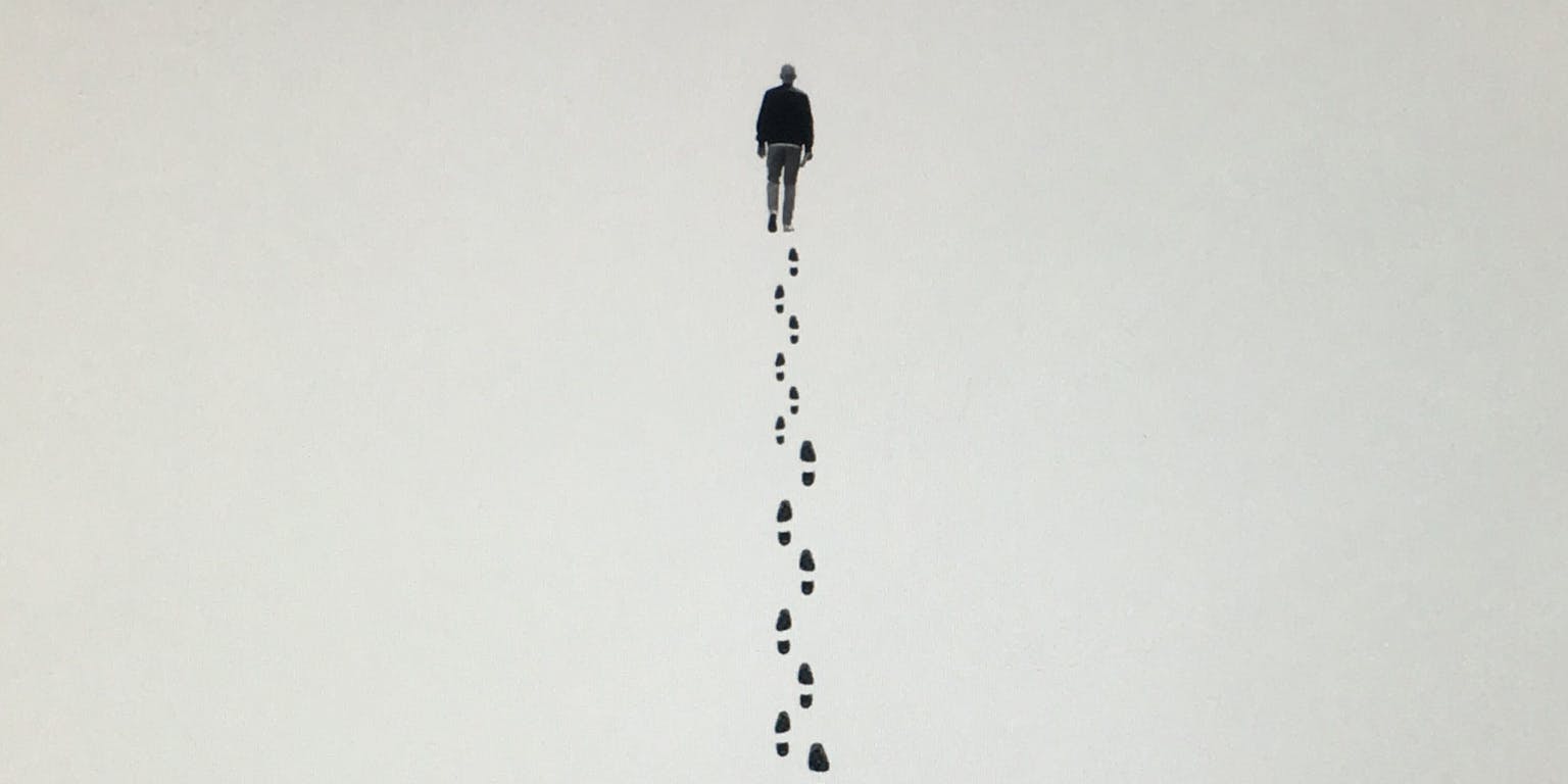 Een tekening van een persoon die aan het wandelen is. Er zijn voetsporen te zien.