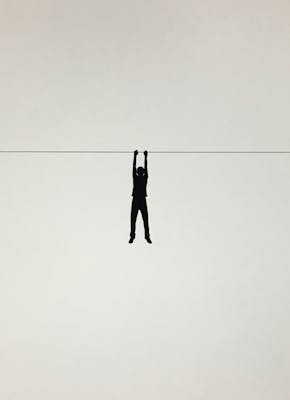 Een silhouet van een persoon die aan een draad hangt.