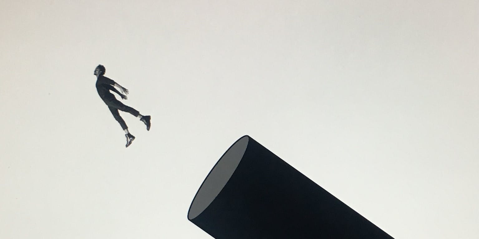 Een silhouet van een man die uit een ronde koker springt.