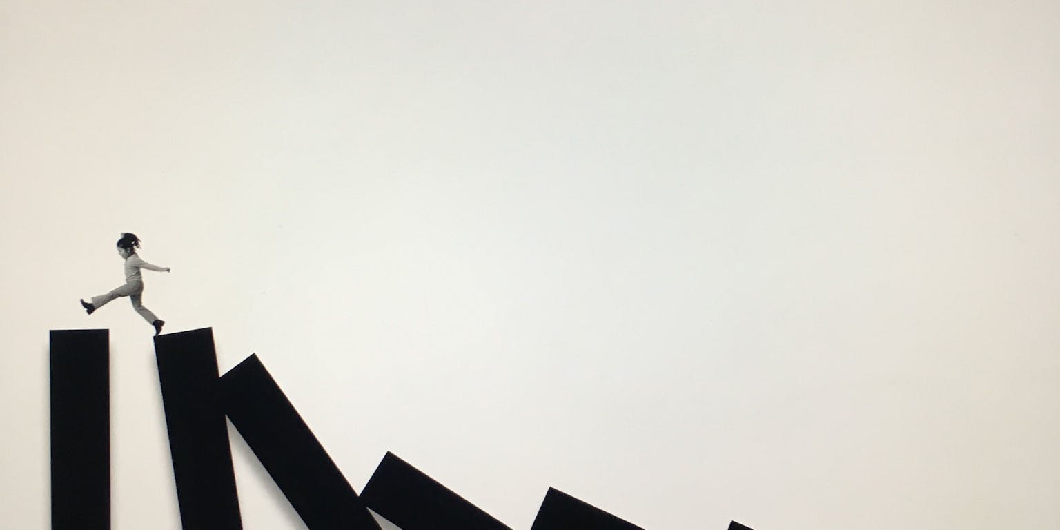 Een man rent over een reeks omvallende dominostenen