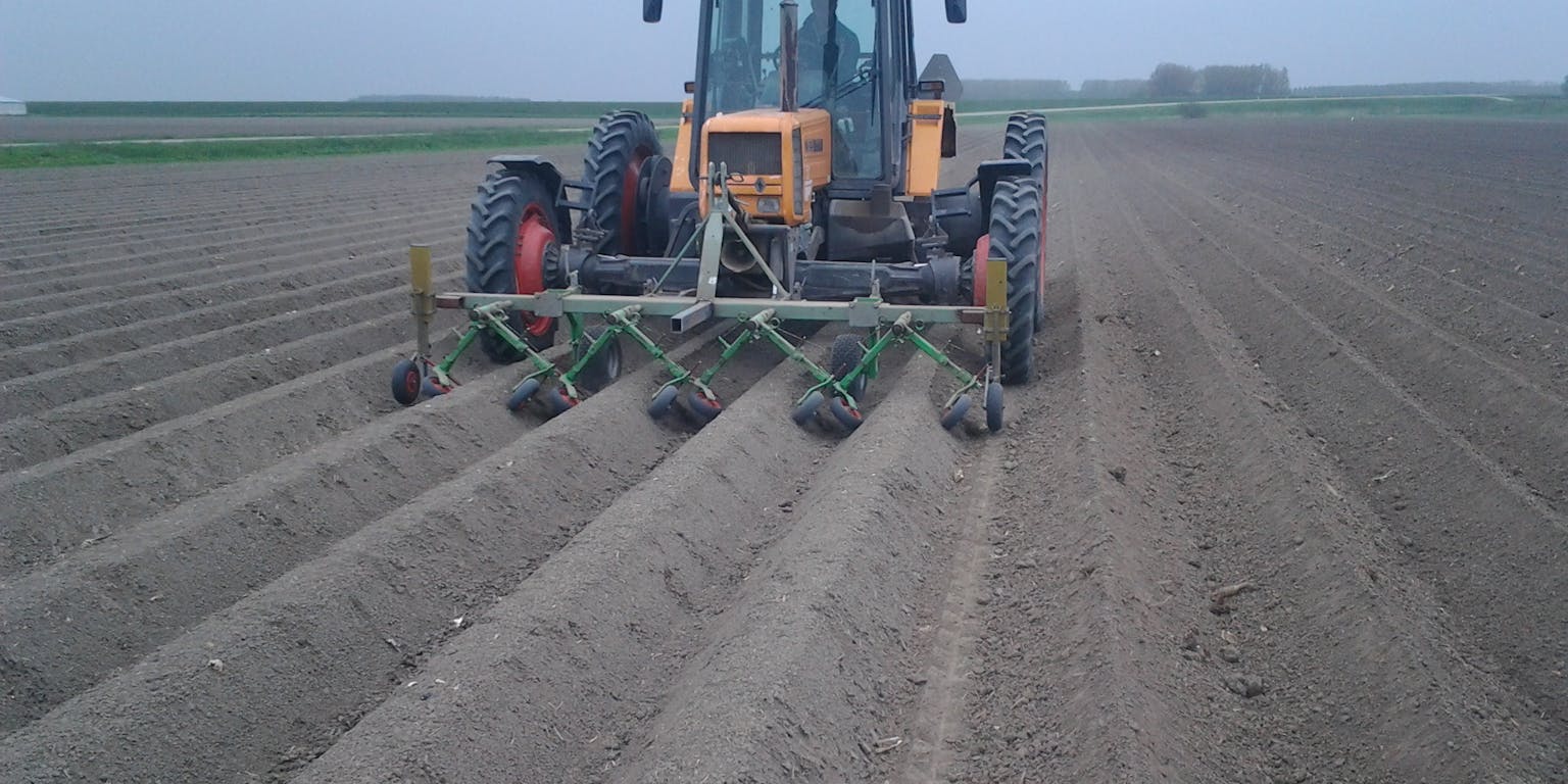 Een tractor op een veld die een bodemvriendelijke schoffelaar gebruikt.