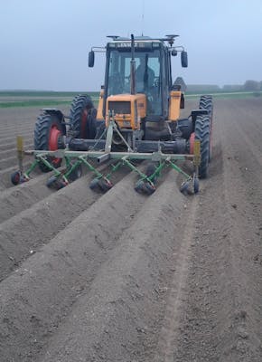 Een tractor op een veld die een bodemvriendelijke schoffelaar gebruikt.