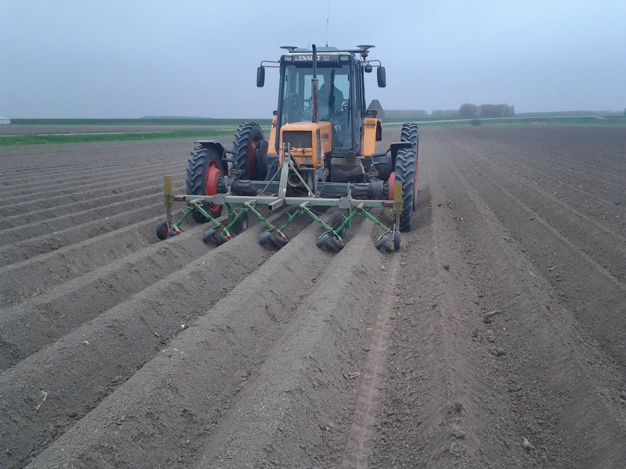 Een tractor op een veld die een bodemvriendelijke schoffelaar gebruikt.