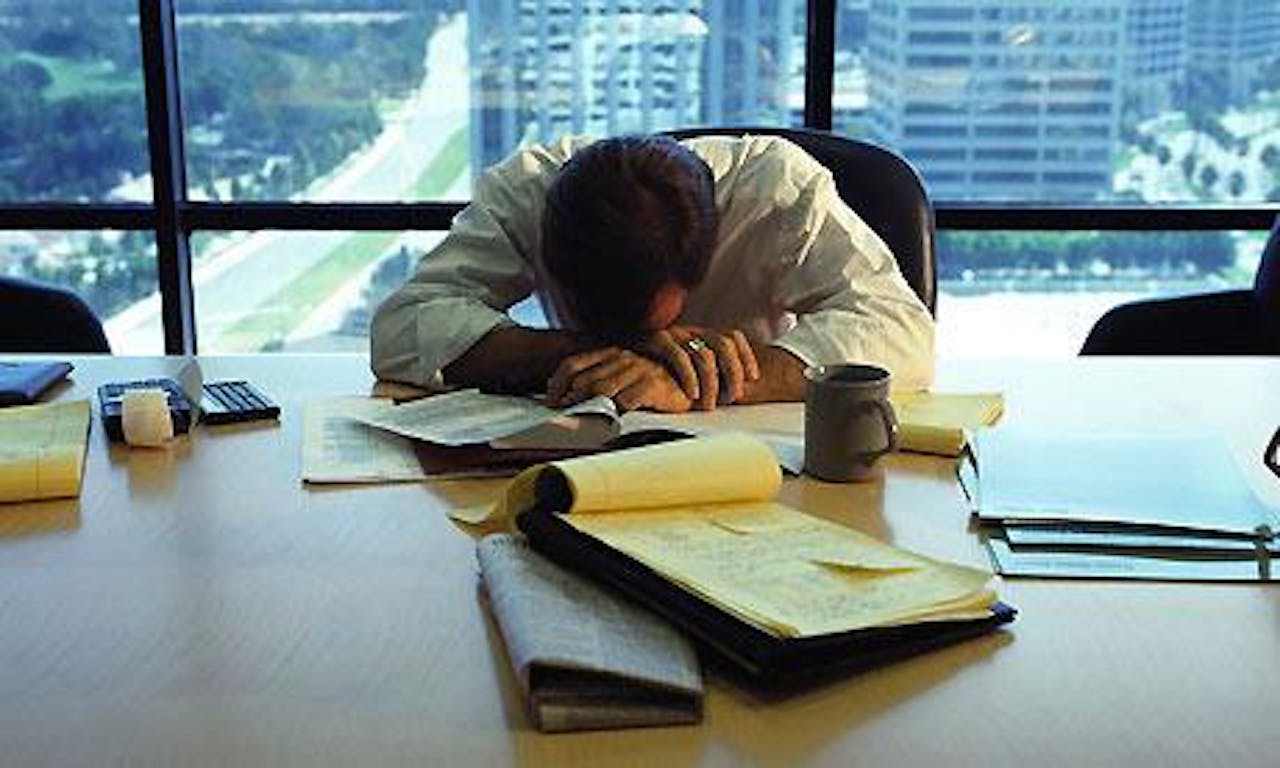 Een man slaapt aan een bureau in een kantoor.