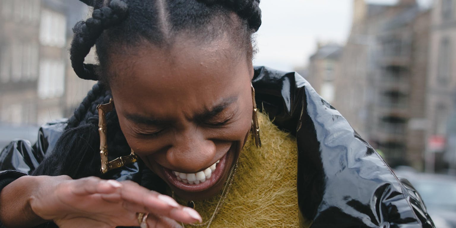 Een vrouw in een zwart jasje maakt een gebaar met haar handen.