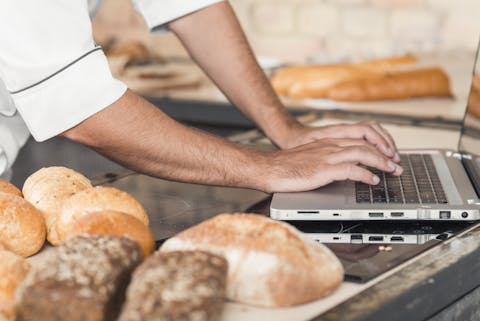 Met het niet-meer-zo-geheime Kaneelbroodjesrecept kunnen hackers de bakkerij afpersen. Een man tikt op zijn laptop met allemaal brood om zich heen