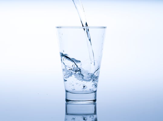 Close-up van een glas waar water in wordt geschonken.