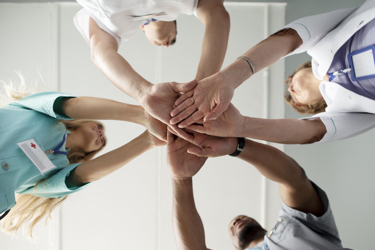 doktoren werken samen en houden hun handen bij elkaar om teamwerk uit te beelden