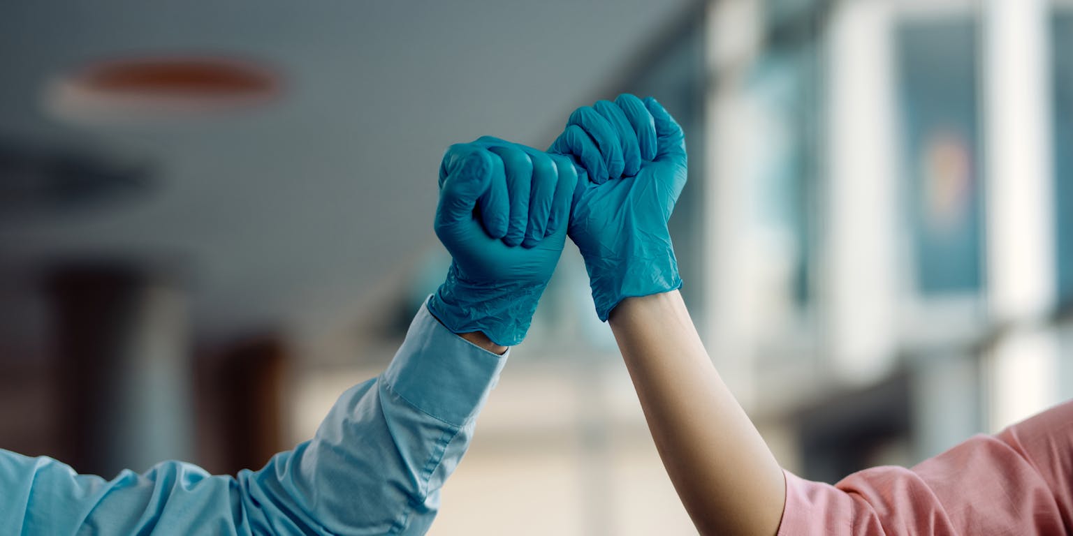 dokters met blauwe handschoenen aan geven elkaar een vuist
