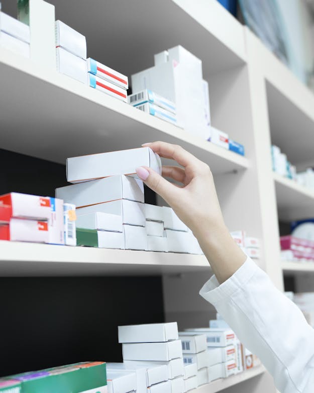 Patiënten krijgen vaak hele doosjes medicijnen, terwijl ze lang niet altijd alle pillen nodig hebben. Hand van verpleegkundige pakt een doosje pillen uit een grote kast met medicijnen
