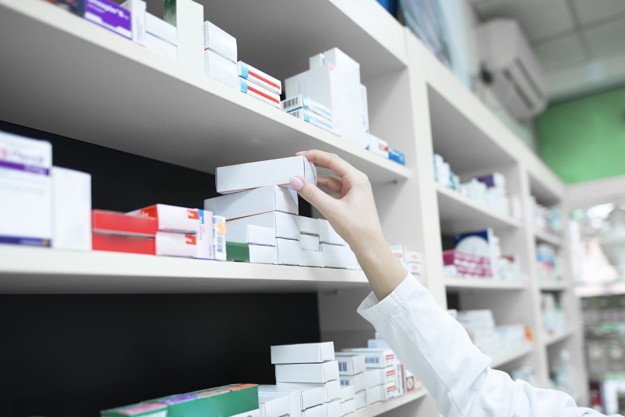Hand van verpleegkundige pakt een doosje pillen uit een grote kast met medicijnen