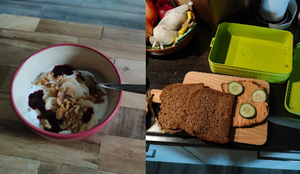 Links een ontbijt met yoghurt en muesli in een bakje met lepel op een houten tafel, rechts drie bruine boterhammen in een groene lunchbox, een van de boterhammen is pindakaas met komkommer