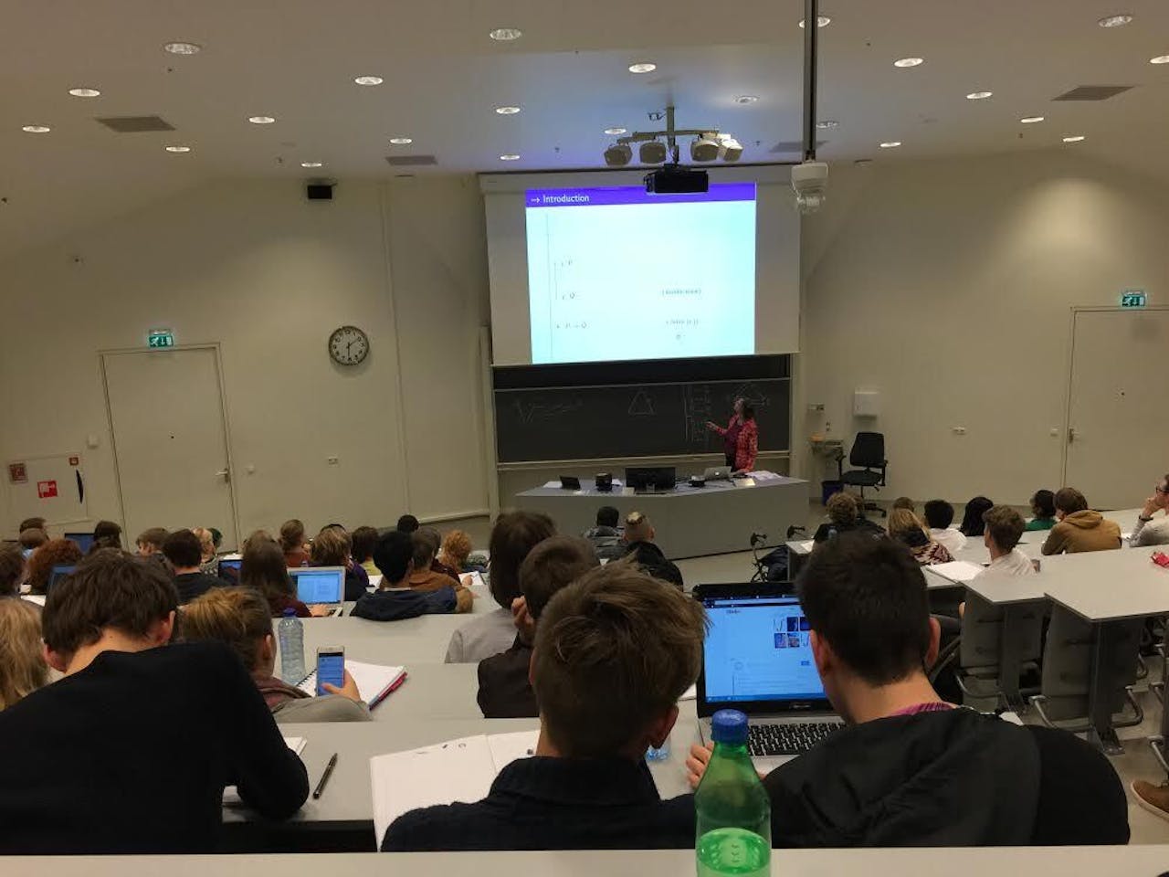 Een collegezaal met veel mensen die aan bureaus zitten.