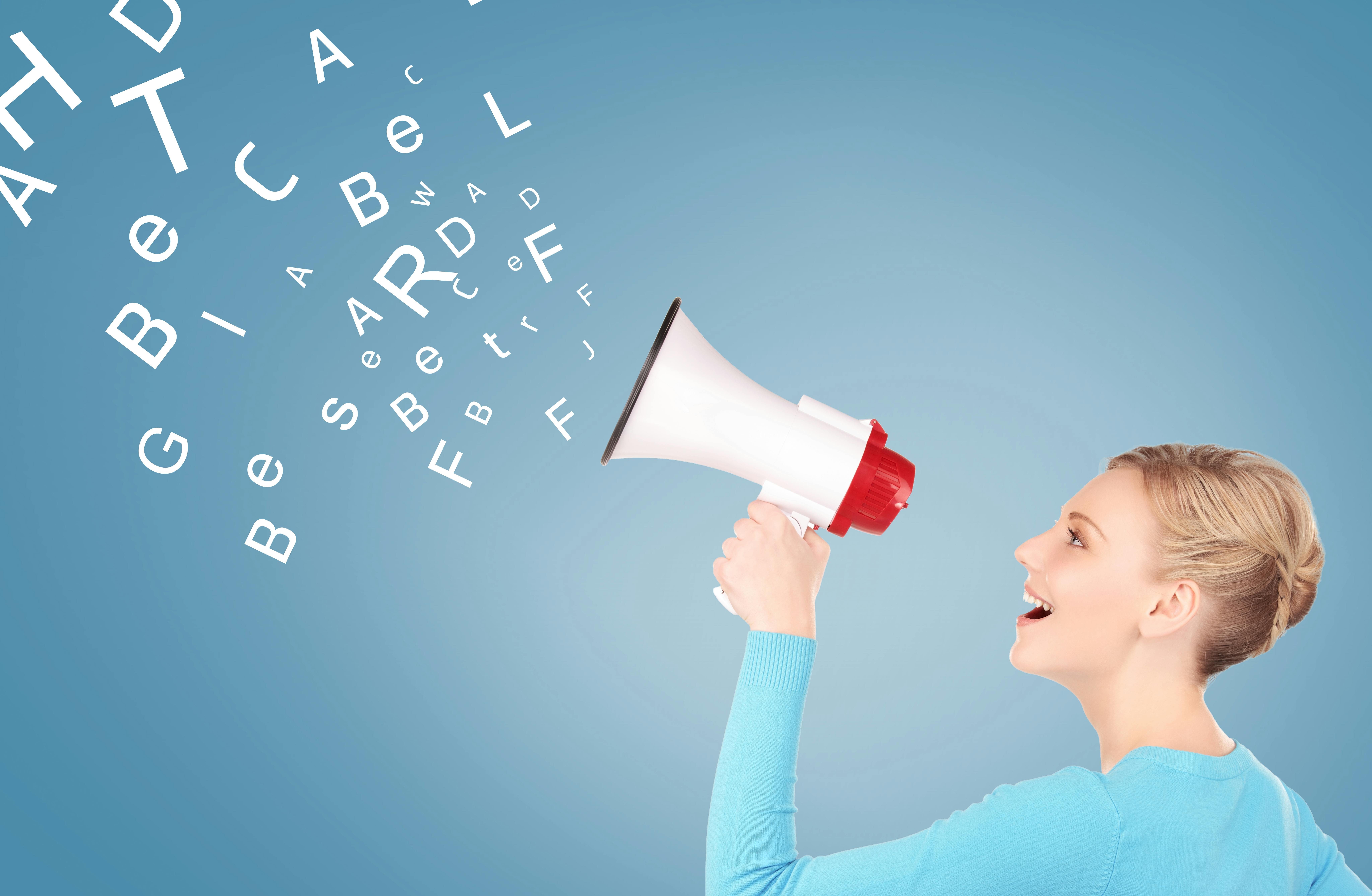 vrouw met megafoon kijkt naar alfabetletters