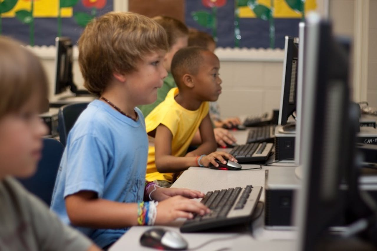 Een groep kinderen leert werken op een computer.