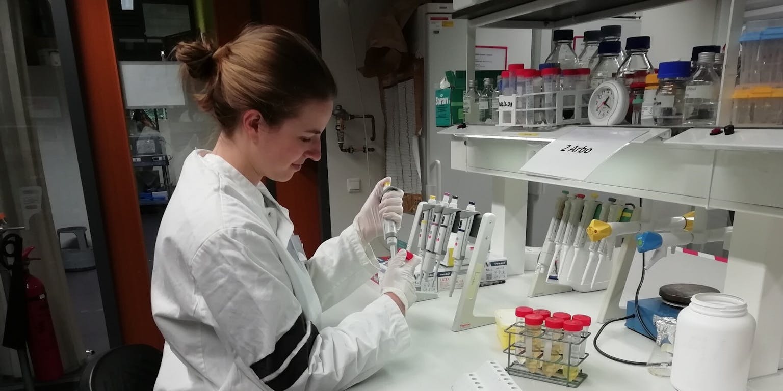 Een vrouw in een laboratoriumjas die aan een monster werkt.