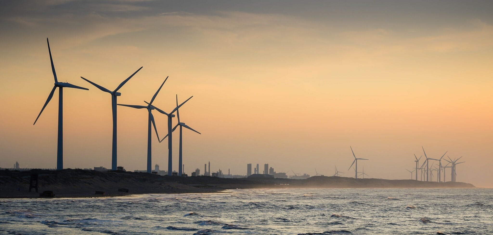 Windturbines op het strand bij zonsondergang.
