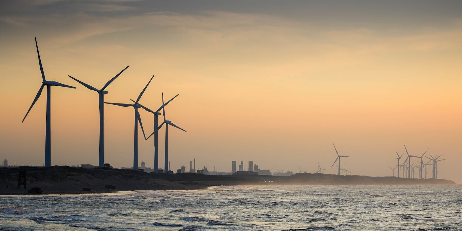 Windturbines op het strand bij zonsondergang.