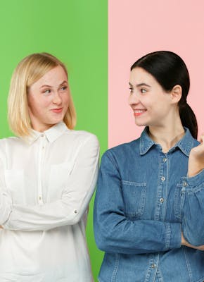 twee jonge vrouwen met een groene en roze achtergrond moeten kiezen tussen een gezonde appel eten, of een ongezond cakeje
