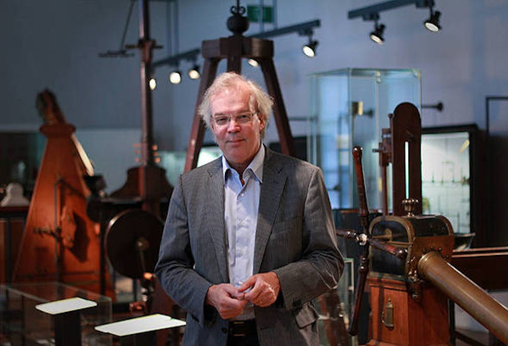 Een kleurenfoto van Wetenschapshistoricus Dirk van Delft. Op de achtergrond staat oude apparatuur.