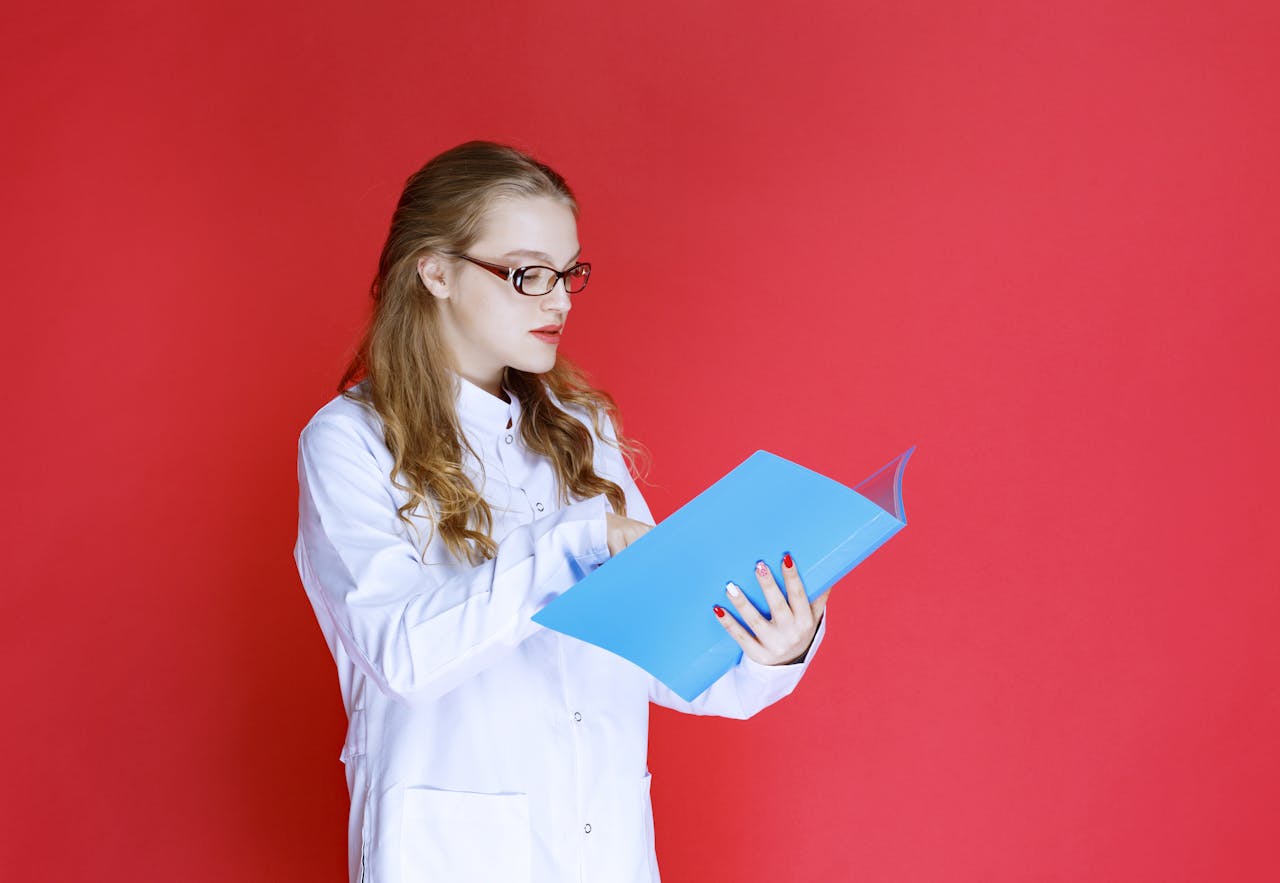 Een vrouw met een bril op en een witte jas leest een publicatie