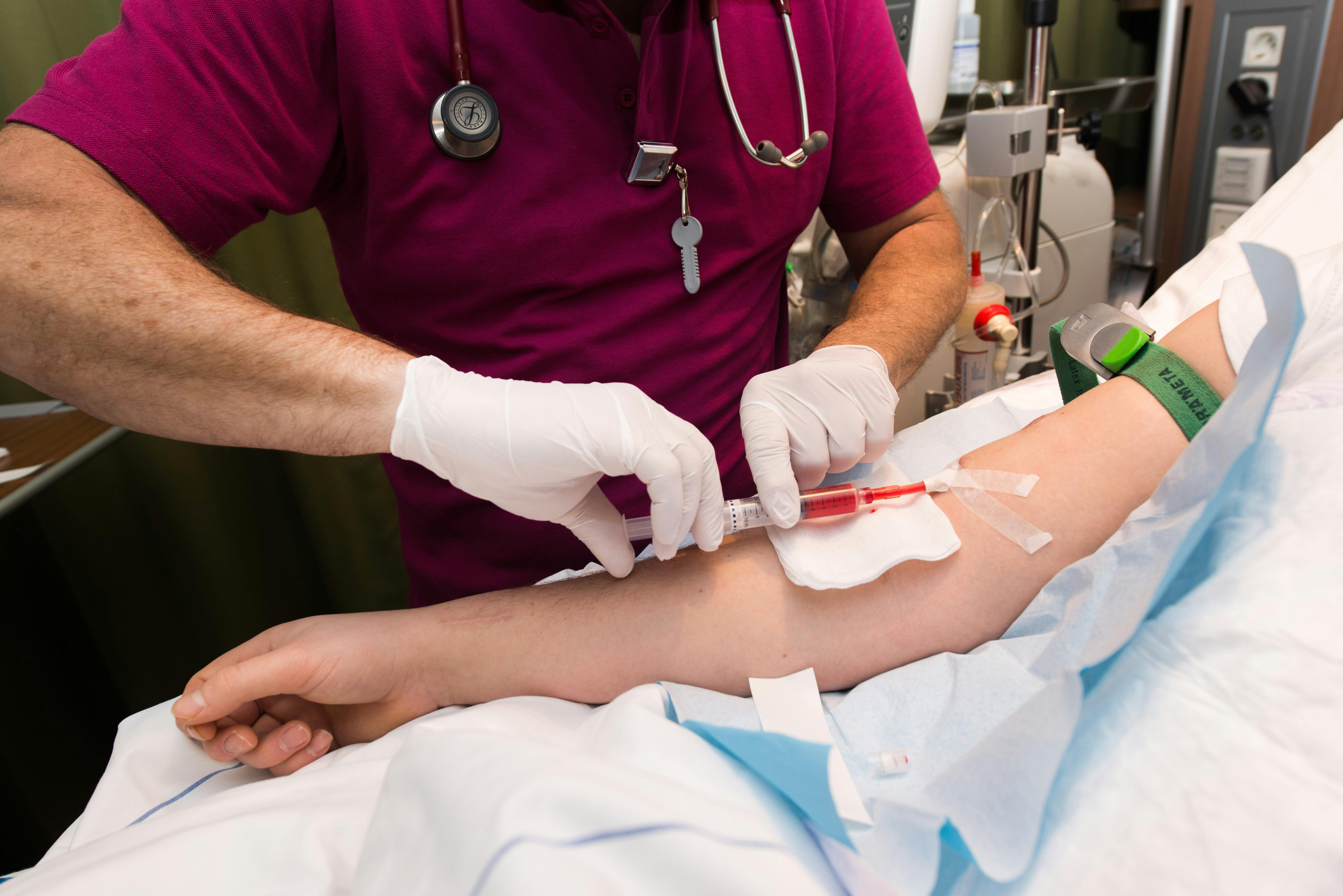 Een verpleegster die een injectie geeft aan een patiënt in een ziekenhuisbed.